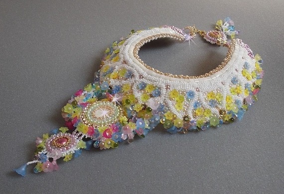 Plastron Envol&eacute;e Fleurie Haute Couture brod&eacute; avec des cabochons Nacre et R&eacute;sine aux couleurs Fuchsia et Ivoire, s&rsquo;ajoute des fleurs lucites, feuilles en verre, chatons et perles en Cristal.