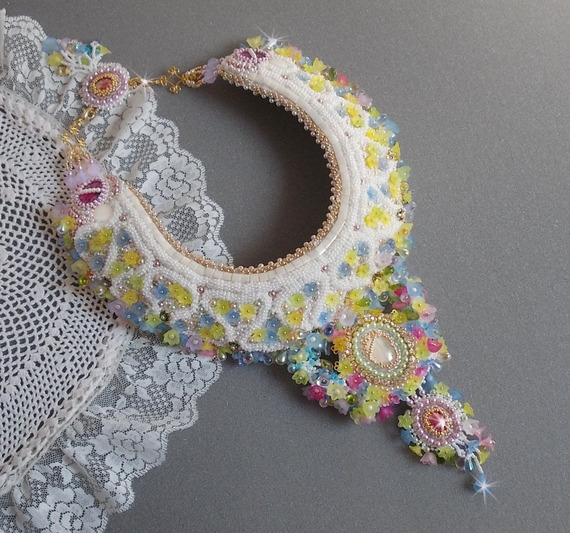 Plastron Envol&eacute;e Fleurie Haute Couture brod&eacute; avec des cabochons Nacre et R&eacute;sine aux couleurs Fuchsia et Ivoire, s&rsquo;ajoute des fleurs lucites, feuilles en verre, chatons et perles en Cristal.