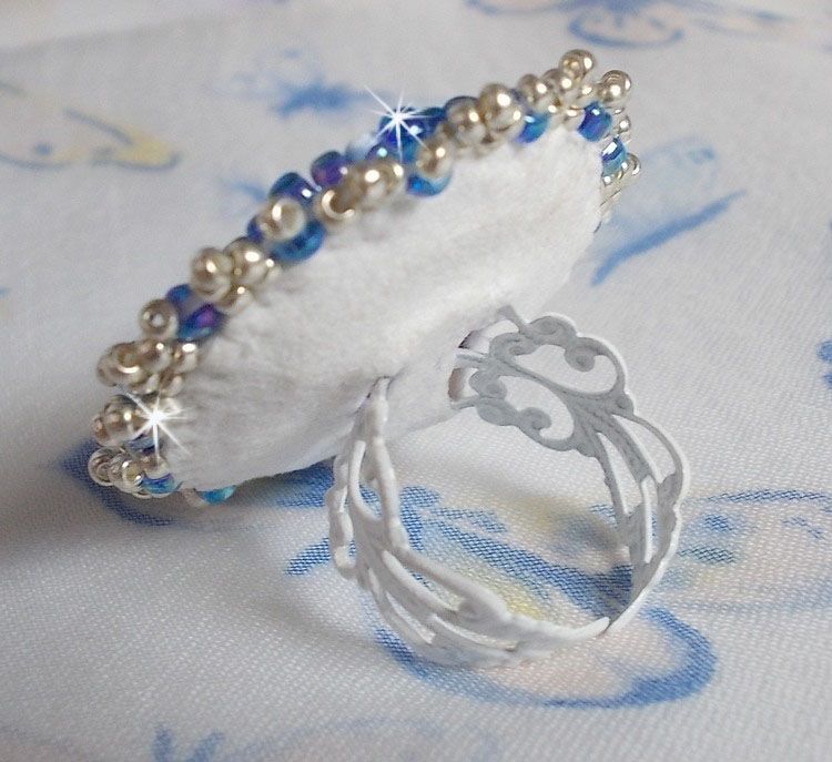 Bague Azur brod&eacute;e avec un cabochon en Cristal de couleur Antique Pink &agrave; laquelle s'ajoute des rocailles et perles rondes nacr&eacute;es. Le tout est mont&eacute; sur une bague filigran&eacute;e Blanche