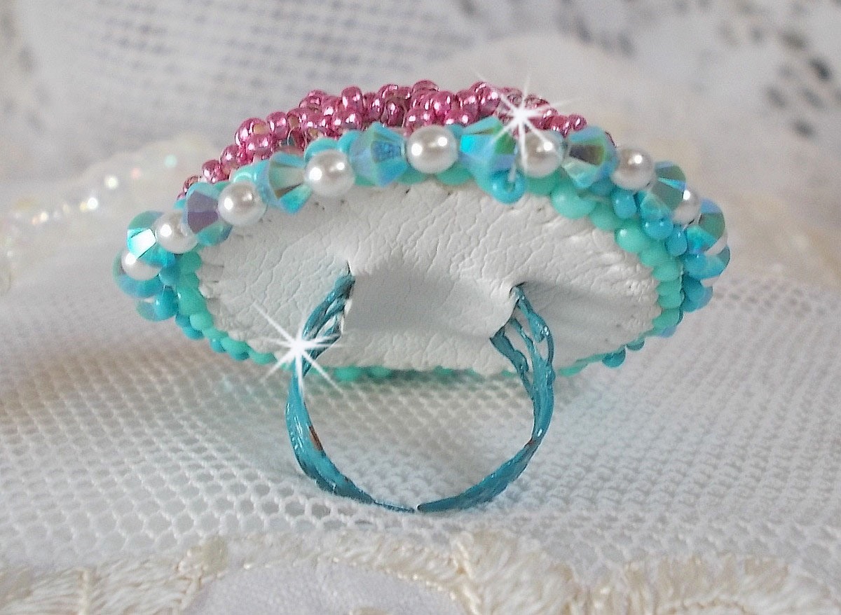 Bague Beauty Alicia Blue brod&eacute;e avec un cabochon en Cristal Bleu, perles nacr&eacute;es Blanches, toupies Turquoises AB2x et rocailles. Le tout est mont&eacute; sur une bague filigran&eacute;e Bleue, un style contemporain
