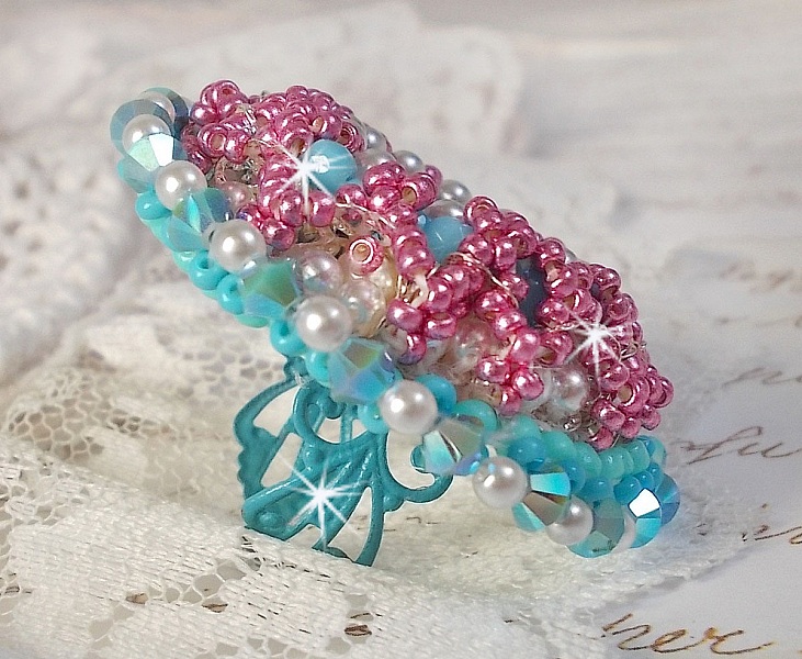 Bague Beauty Alicia Blue brod&eacute;e avec un cabochon en Cristal Bleu, perles nacr&eacute;es Blanches, toupies Turquoises AB2x et rocailles. Le tout est mont&eacute; sur une bague filigran&eacute;e Bleue, un style contemporain
