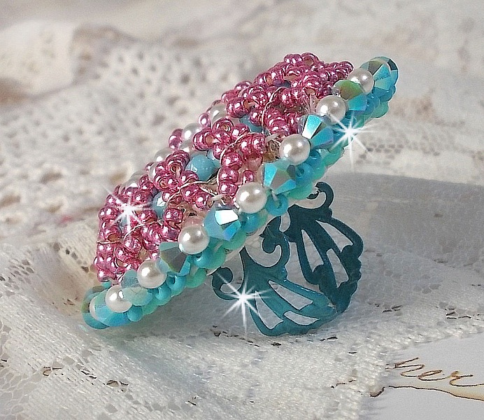 Bague Beauty Alicia Blue brod&eacute;e avec un cabochon en Cristal Bleu, perles nacr&eacute;es Blanches, toupies Turquoises AB2x et rocailles. Le tout est mont&eacute; sur une bague filigran&eacute;e Bleue, un style contemporain