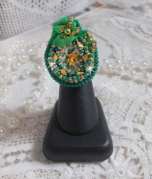 Bague Belle Emeraude brod&eacute;e avec un cabochon ovale en c&eacute;ramique repr&eacute;sentant une rose Jaune sur fond Blanc, un tissu l&eacute;ger de couleur Vert, des perles rondes nacr&eacute;es et des rocailles Dor&eacute;es