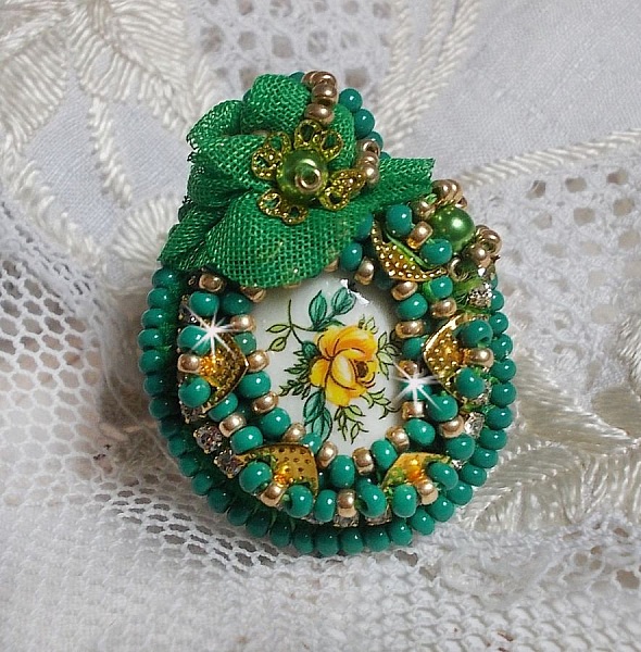 Bague Belle Emeraude brod&eacute;e avec un cabochon ovale en c&eacute;ramique repr&eacute;sentant une rose Jaune sur fond Blanc, un tissu l&eacute;ger de couleur Vert, des perles rondes nacr&eacute;es et des rocailles Dor&eacute;es