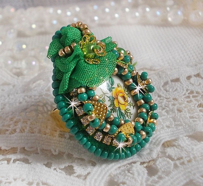 Bague Belle Emeraude brod&eacute;e avec un cabochon ovale en c&eacute;ramique repr&eacute;sentant une rose Jaune sur fond Blanc, un tissu l&eacute;ger de couleur Vert, des perles rondes nacr&eacute;es et des rocailles Dor&eacute;es
