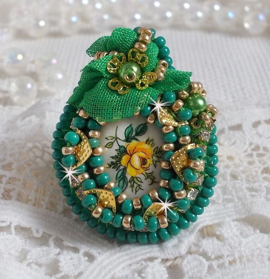 Bague Belle Emeraude brod&eacute;e avec un cabochon ovale en c&eacute;ramique repr&eacute;sentant une rose Jaune sur fond Blanc, un tissu l&eacute;ger de couleur Vert, des perles rondes nacr&eacute;es et des rocailles Dor&eacute;es