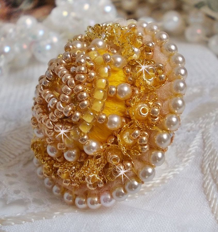 Bague artisanale brodée avec perles nacrées et rocailles dorées.