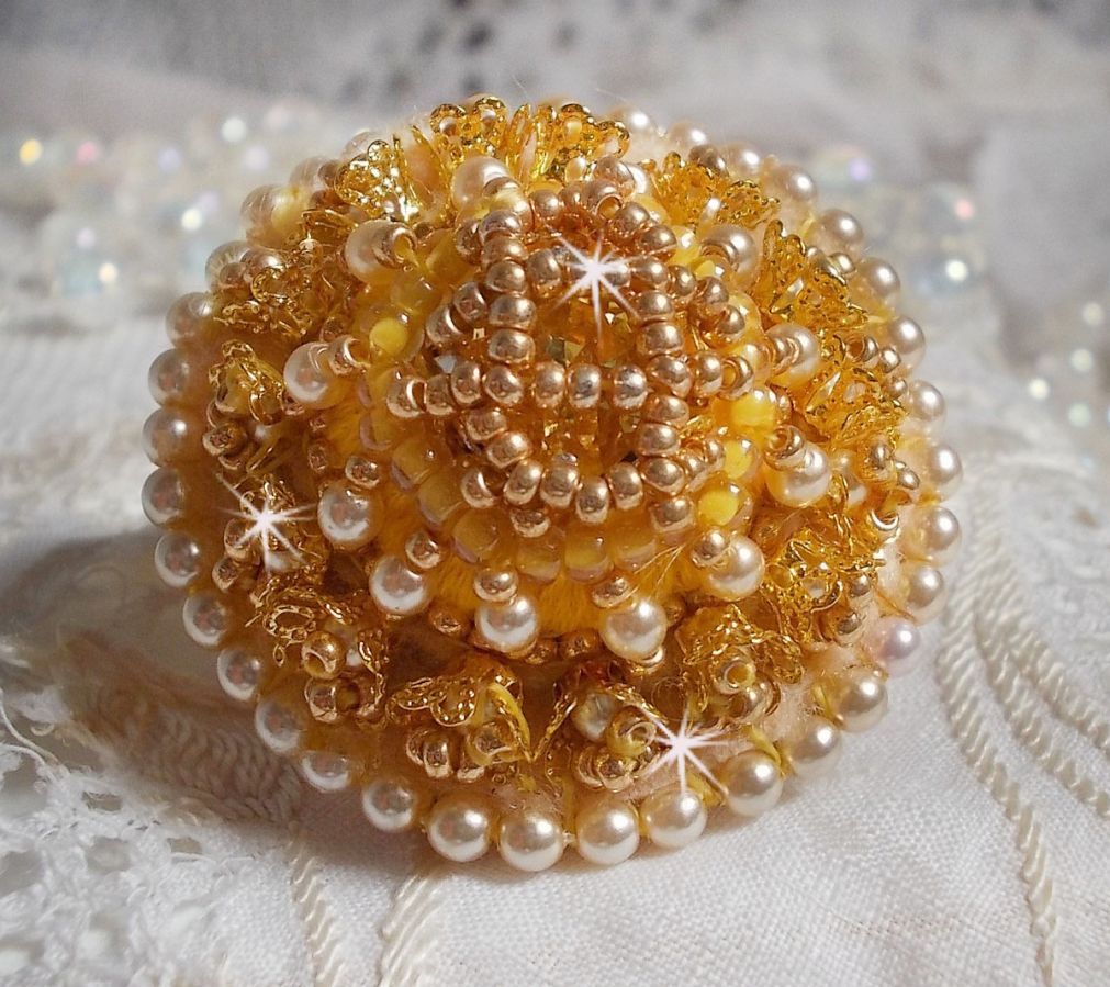 Bague artisanale brodée en perles dorées et nacrées.