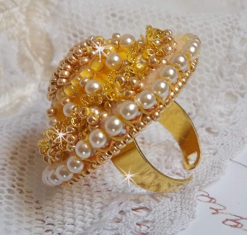 Bague artisanale brodée jaune avec perles nacrées et dorées.