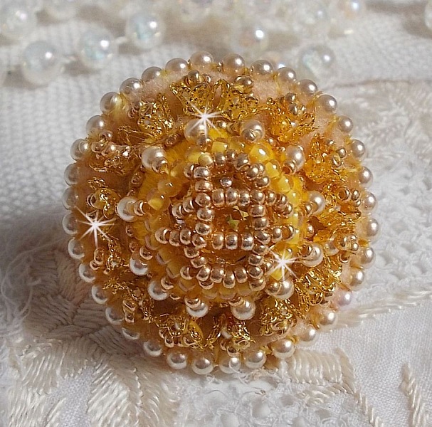 Bague artisanale brodée jaune et dorée avec perles nacrées.