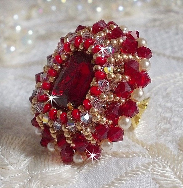 Bague Rubis brod&eacute;e avec un cabochon rectangulaire Ruby, orn&eacute;e de chatons mont&eacute;s en Cristal avec des perles rondes nacr&eacute;es en verre Ivoire, rocailles Dor&eacute;es, des toupies Cristal AB et Burgundy.
