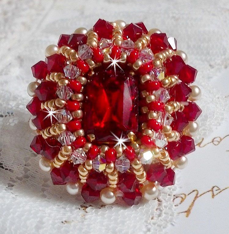 Bague Rubis brod&eacute;e avec un cabochon rectangulaire Ruby, orn&eacute;e de chatons mont&eacute;s en Cristal avec des perles rondes nacr&eacute;es en verre Ivoire, rocailles Dor&eacute;es, des toupies Cristal AB et Burgundy.