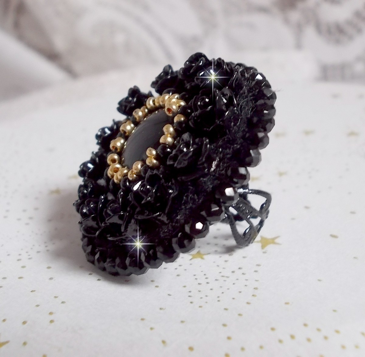 Bague Cl&eacute;op&acirc;tra brod&eacute;e avec une pierre de gemme : l'onyx Noir avec des cabochons ronds en forme de roses Noires, des rocailles Dor&eacute;es et des perles rondes facett&eacute;es aplaties sur une bague filigran&eacute;e 