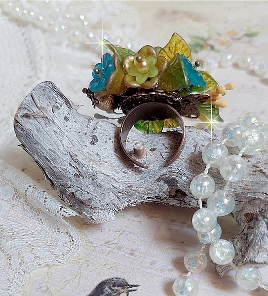 Bague C&eacute;zanne mont&eacute;e avec des petites fleurs lucites peintes &agrave; la main &agrave; laquelle s&rsquo;ajoute des feuilles, cristaux, perles, &eacute;tamines, grosses rocailles, perles nacr&eacute;es et m&eacute;tal sur une bague en Laiton