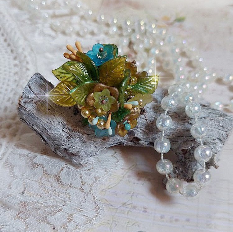 Bague C&eacute;zanne mont&eacute;e avec des petites fleurs lucites peintes &agrave; la main &agrave; laquelle s&rsquo;ajoute des feuilles, cristaux, perles, &eacute;tamines, grosses rocailles, perles nacr&eacute;es et m&eacute;tal sur une bague en Laiton