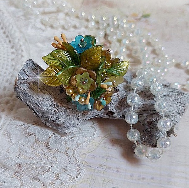 Bague C&eacute;zanne mont&eacute;e avec des petites fleurs lucites peintes &agrave; la main &agrave; laquelle s&rsquo;ajoute des feuilles, cristaux, perles, &eacute;tamines, grosses rocailles, perles nacr&eacute;es et m&eacute;tal sur une bague en Laiton