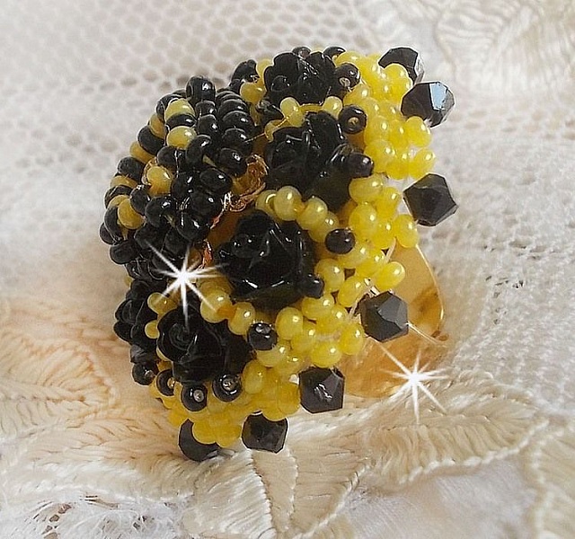 Bague Dorine brod&eacute;e avec un chaton Cristal/Dor&eacute; orn&eacute;e de roses en R&eacute;sine Noire &agrave; laquelle s&rsquo;ajoute des rocailles Jaunes et Jet mont&eacute;es en D&ocirc;me. L&rsquo;arri&egrave;re est en cuir vachette sur une bague Laiton