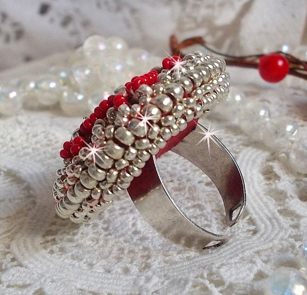 Bague Drigon Red brod&eacute;e avec un cabochon carr&eacute; Rouge sur une estampe Argent&eacute;e. Orn&eacute;e de chatons en Cristal puis model&eacute;e avec des rocailles et perles. Le tout est mont&eacute; sur une bague r&eacute;glable argent&eacute;e 
