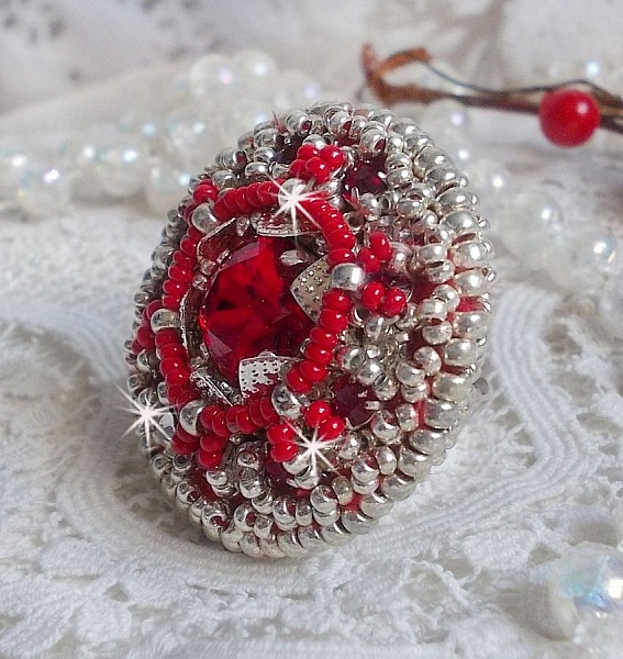 Bague Drigon Red brod&eacute;e avec un cabochon carr&eacute; Rouge sur une estampe Argent&eacute;e. Orn&eacute;e de chatons en Cristal puis model&eacute;e avec des rocailles et perles. Le tout est mont&eacute; sur une bague r&eacute;glable argent&eacute;e 