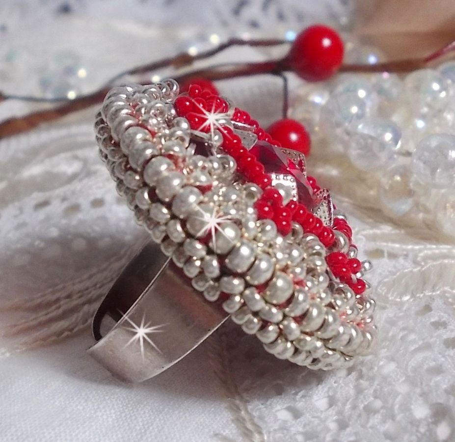 Bague Drigon Red brod&eacute;e avec un cabochon carr&eacute; Rouge sur une estampe Argent&eacute;e. Orn&eacute;e de chatons en Cristal puis model&eacute;e avec des rocailles et perles. Le tout est mont&eacute; sur une bague r&eacute;glable argent&eacute;e 