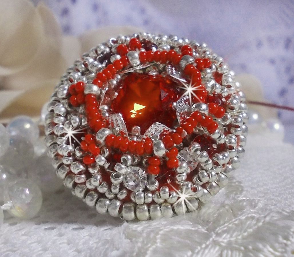 Bague Drigon Red brod&eacute;e avec un cabochon carr&eacute; Rouge sur une estampe Argent&eacute;e. Orn&eacute;e de chatons en Cristal puis model&eacute;e avec des rocailles et perles. Le tout est mont&eacute; sur une bague r&eacute;glable argent&eacute;e 