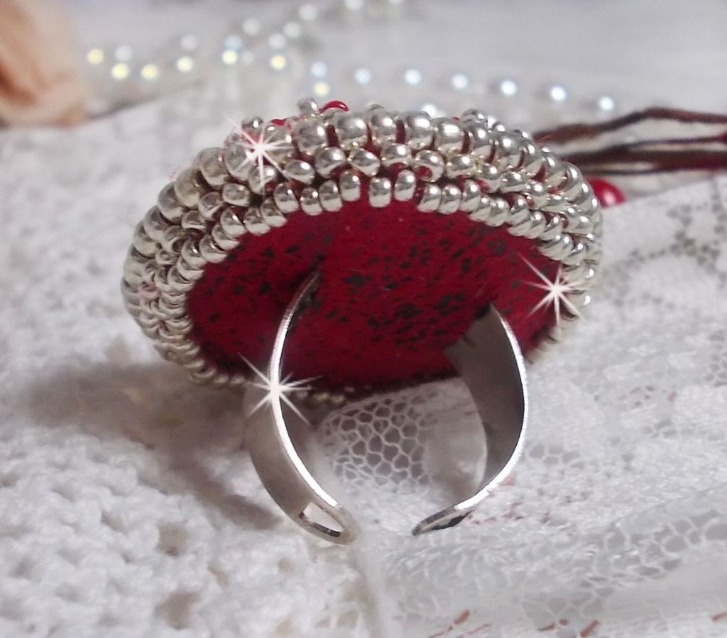 Bague Drigon Red brod&eacute;e avec un cabochon carr&eacute; Rouge sur une estampe Argent&eacute;e. Orn&eacute;e de chatons en Cristal puis model&eacute;e avec des rocailles et perles. Le tout est mont&eacute; sur une bague r&eacute;glable argent&eacute;e 