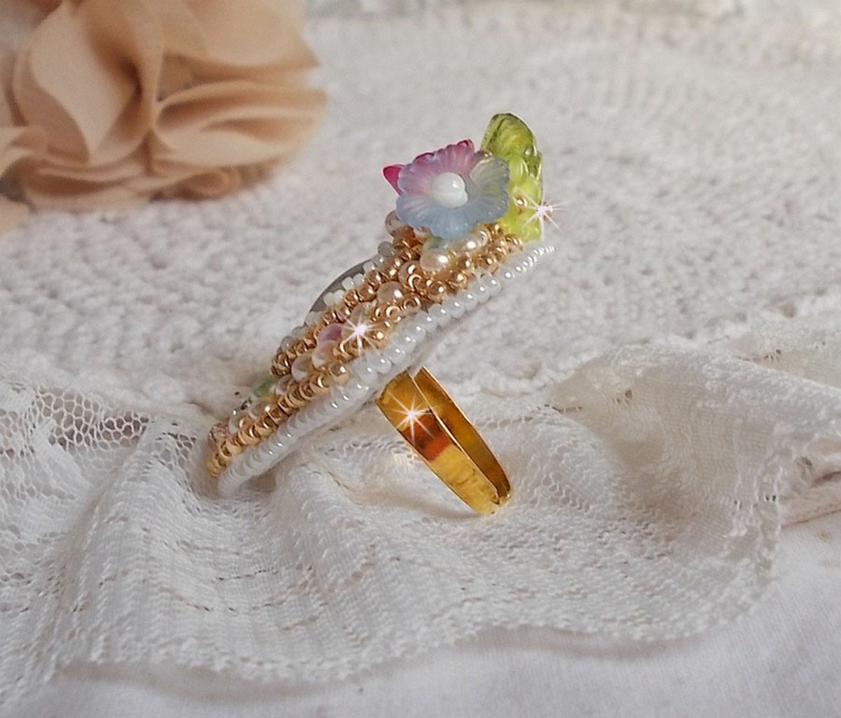 Bague Envol&eacute;e Fleurie brod&eacute;e avec un cabochon ovale Olivine en r&eacute;sine, orn&eacute;e de perles rondes nacr&eacute;es, des rocailles, fleurs Lucites, mini gouttes, chaton en Cristal et perles rondes aplaties.