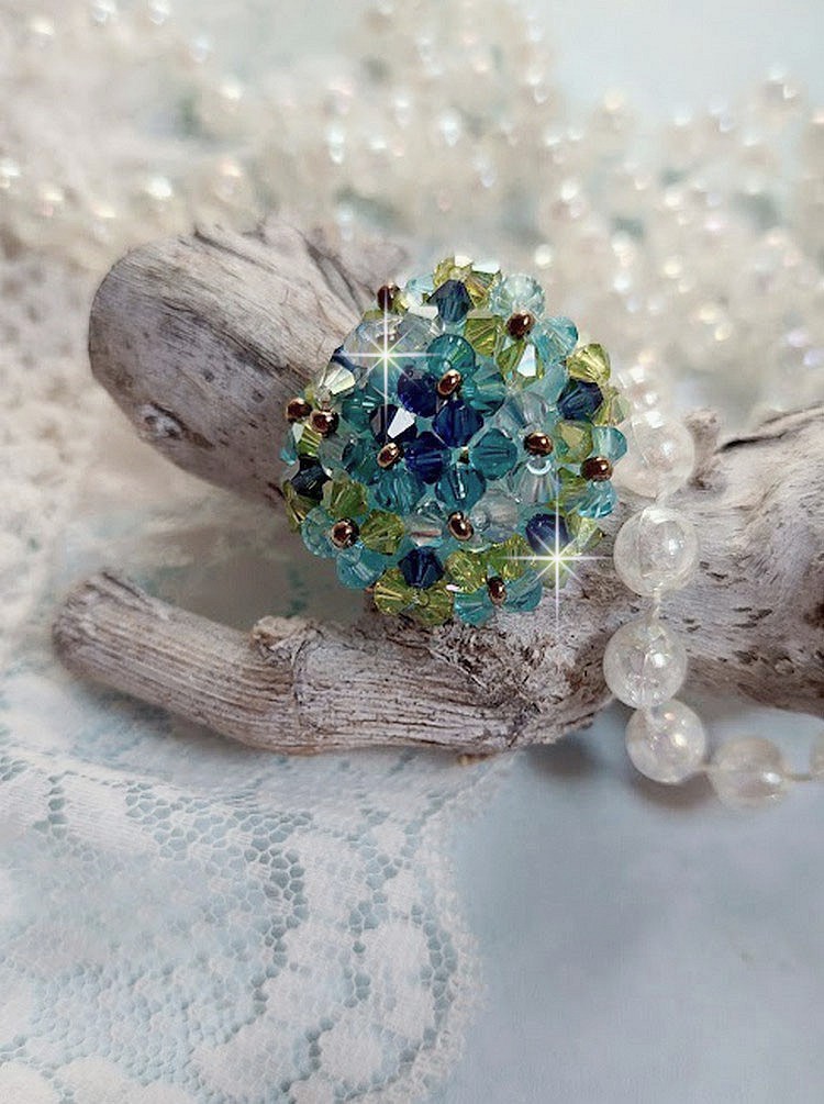 Bague Esp&eacute;rance mont&eacute;e avec toupies Aquamarine AB, Blue Zircon, Capri Blue, Olivine AB, Cristal avec des facettes entrelac&eacute;es avec des rocailles. Elle s&rsquo;adaptera parfaitement &agrave; votre doigt