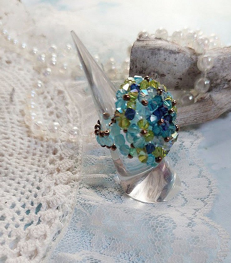Bague Esp&eacute;rance mont&eacute;e avec toupies Aquamarine AB, Blue Zircon, Capri Blue, Olivine AB, Cristal avec des facettes entrelac&eacute;es avec des rocailles. Elle s&rsquo;adaptera parfaitement &agrave; votre doigt