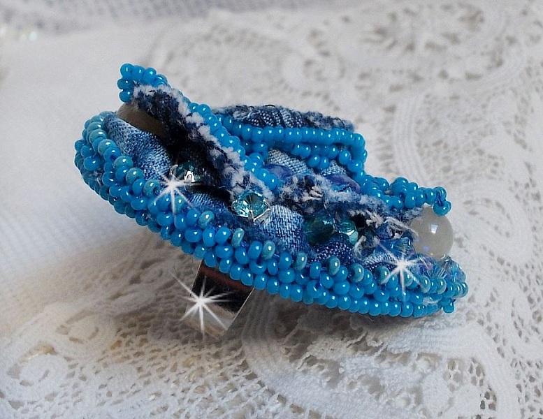 Bague Far West tout en jean brod&eacute;e avec des pierres de Gemme : Le Sodalite et le Jade Jaune &agrave; laquelle s'ajoute un tissu en Jean, un tissu mouchet&eacute; de fleurs avec des chatons en Cristal et des toupies