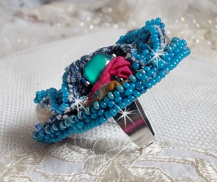 Bague Far West tout en jean brod&eacute;e avec des pierres de Gemme : Le Sodalite et le Jade Jaune &agrave; laquelle s'ajoute un tissu en Jean, un tissu mouchet&eacute; de fleurs avec des chatons en Cristal et des toupies