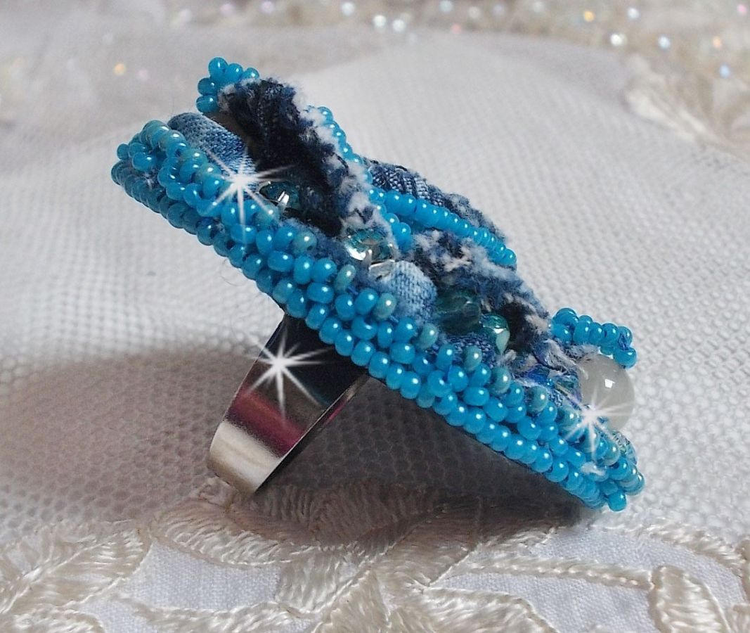 Bague Far West tout en jean brod&eacute;e avec des pierres de Gemme : Le Sodalite et le Jade Jaune &agrave; laquelle s'ajoute un tissu en Jean, un tissu mouchet&eacute; de fleurs avec des chatons en Cristal et des toupies