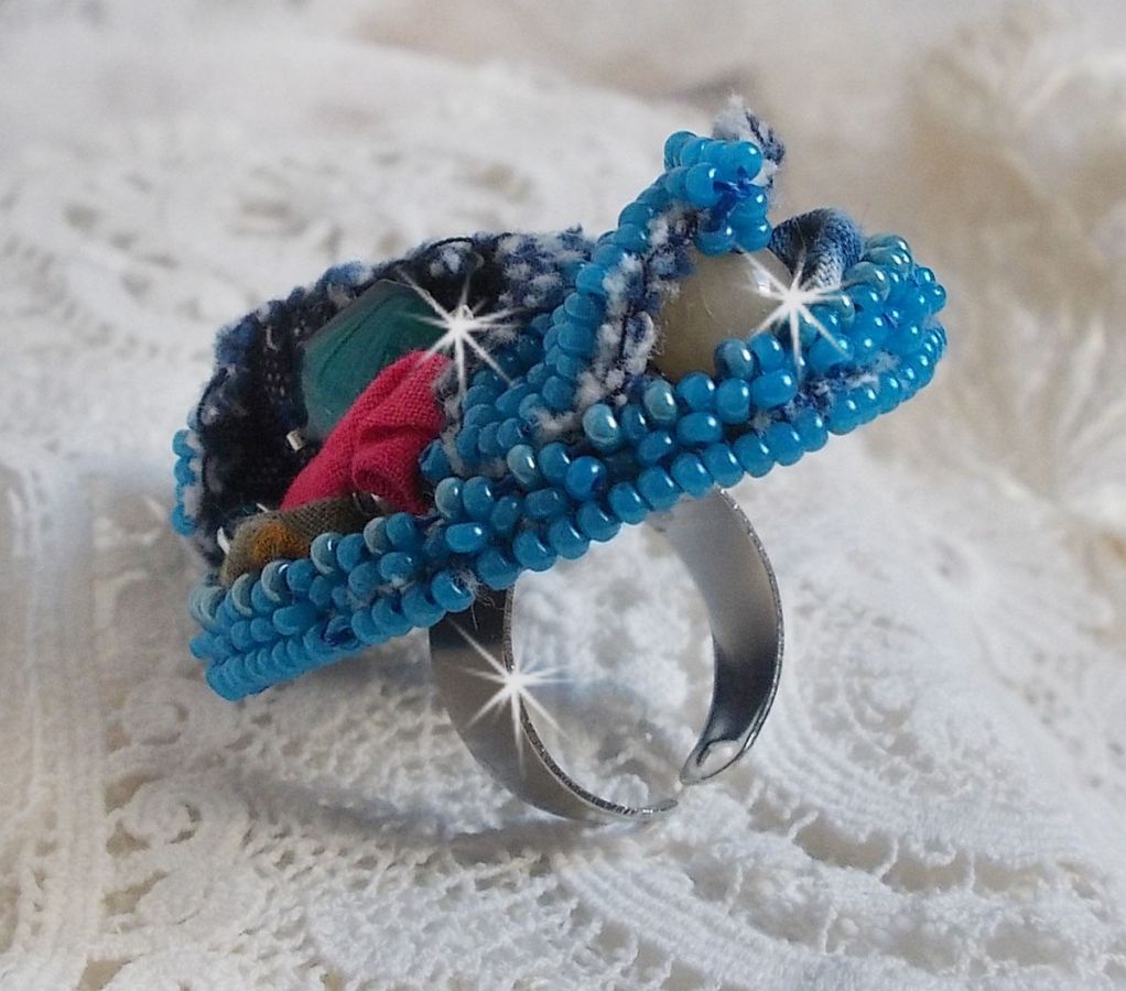 Bague Far West tout en jean brod&eacute;e avec des pierres de Gemme : Le Sodalite et le Jade Jaune &agrave; laquelle s'ajoute un tissu en Jean, un tissu mouchet&eacute; de fleurs avec des chatons en Cristal et des toupies