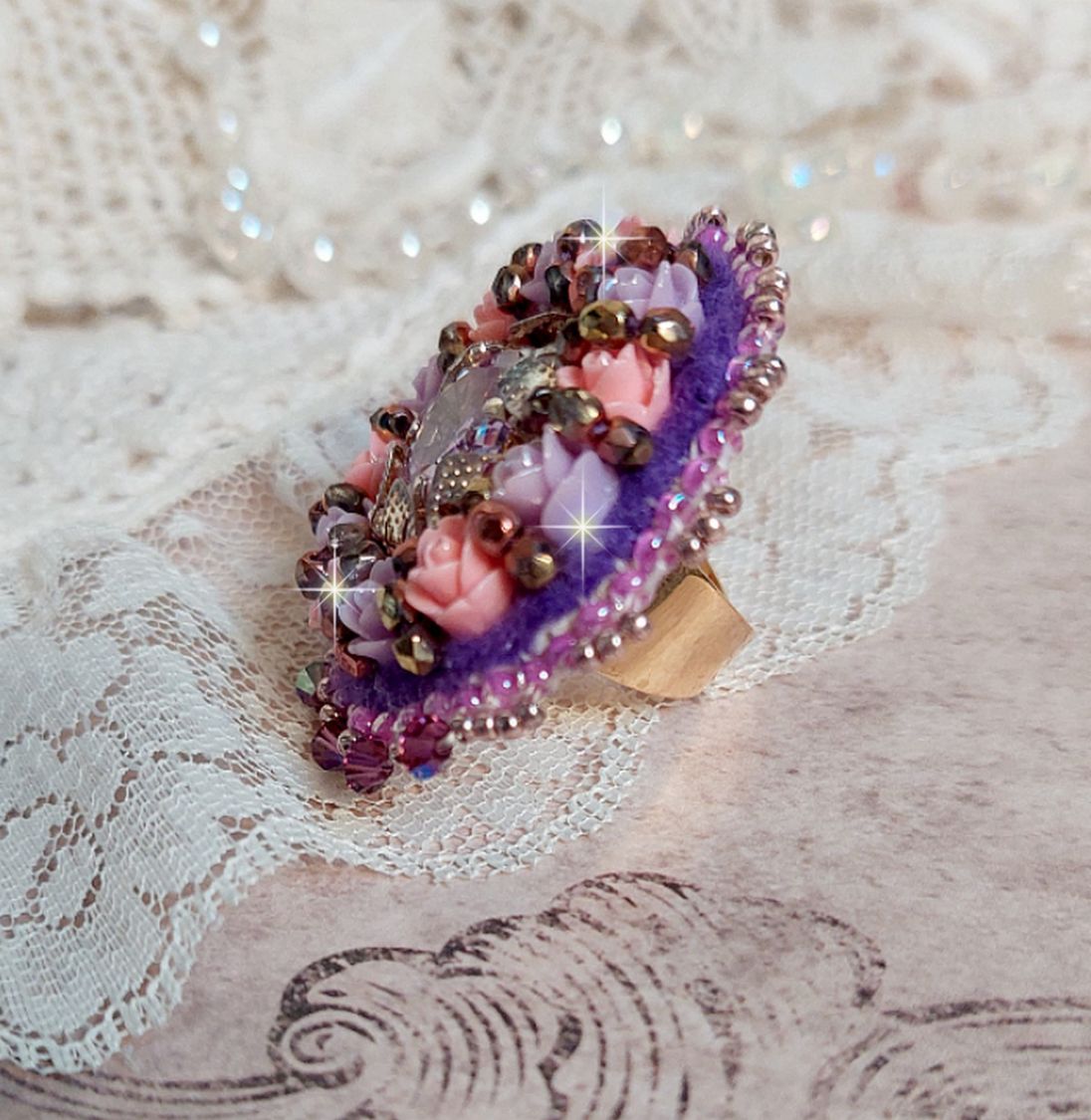 Bague Glace Purple brod&eacute;e avec un cabochon carr&eacute; Violet orn&eacute;e de cabochons roses en r&eacute;sine : Parme et Rose avec des toupies Am&eacute;thyste, facettes en Verre et rocailles. Mont&eacute;s sur une bague Dor&eacute;e