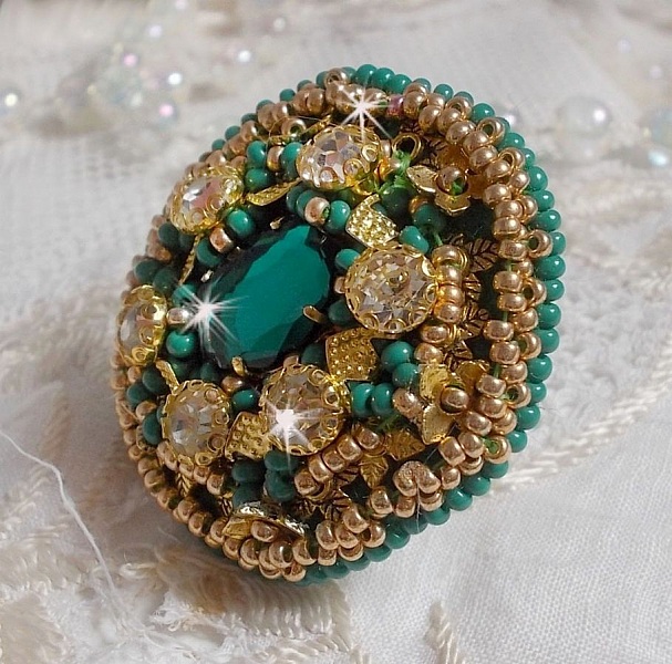 Bague Green Iris brod&eacute;e avec un cabochon Emeraude orn&eacute;e de chatons fleurs cristal sertis, rocailles Vert Opaque et Gold. Mont&eacute;s sur feutrine Verte et sur une bague plateau Dor&eacute;e, un style Contemporain
