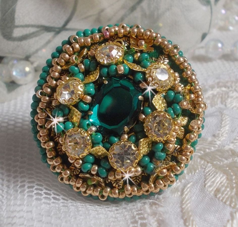 Bague Green Iris brod&eacute;e avec un cabochon Emeraude orn&eacute;e de chatons fleurs cristal sertis, rocailles Vert Opaque et Gold. Mont&eacute;s sur feutrine Verte et sur une bague plateau Dor&eacute;e, un style Contemporain
