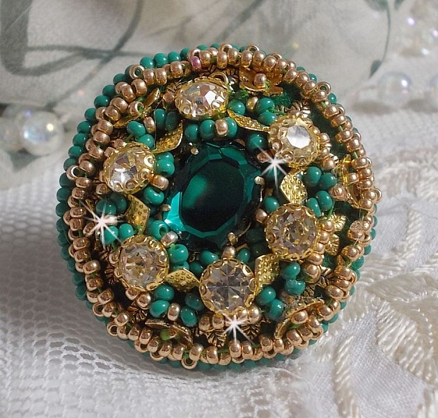 Bague Green Iris brod&eacute;e avec un cabochon Emeraude orn&eacute;e de chatons fleurs cristal sertis, rocailles Vert Opaque et Gold. Mont&eacute;s sur feutrine Verte et sur une bague plateau Dor&eacute;e, un style Contemporain
