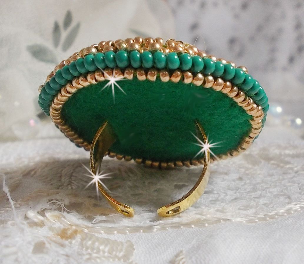 Bague Green Iris brod&eacute;e avec un cabochon Emeraude orn&eacute;e de chatons fleurs cristal sertis, rocailles Vert Opaque et Gold. Mont&eacute;s sur feutrine Verte et sur une bague plateau Dor&eacute;e, un style Contemporain