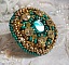 Bague Green Iris brod&eacute;e avec un cabochon Emeraude orn&eacute;e de chatons fleurs cristal sertis, rocailles Vert Opaque et Gold. Mont&eacute;s sur feutrine Verte et sur une bague plateau Dor&eacute;e, un style Contemporain