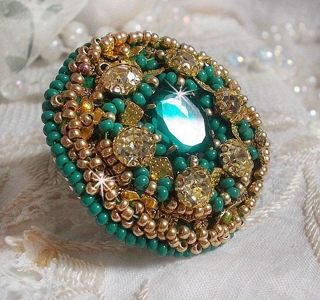 Bague Green Iris brod&eacute;e avec un cabochon Emeraude orn&eacute;e de chatons fleurs cristal sertis, rocailles Vert Opaque et Gold. Mont&eacute;s sur feutrine Verte et sur une bague plateau Dor&eacute;e, un style Contemporain
