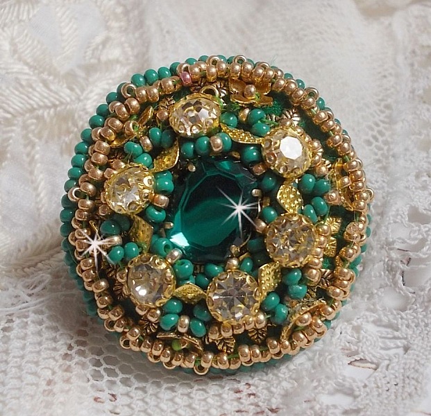 Bague Green Iris brod&eacute;e avec un cabochon Emeraude orn&eacute;e de chatons fleurs cristal sertis, rocailles Vert Opaque et Gold. Mont&eacute;s sur feutrine Verte et sur une bague plateau Dor&eacute;e, un style Contemporain