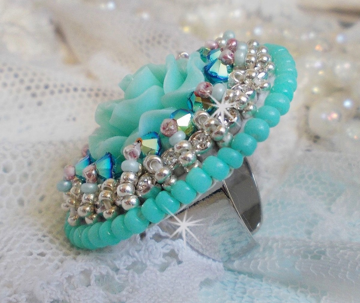 Bague Blue Flowers brod&eacute;e avec un cabochon en forme de rose en r&eacute;sine, cha&icirc;ne strass Cristal, toupies Jet de haute qualit&eacute; AB2X et farfalles ovales. Les couleurs sont : l&rsquo;Argent&eacute; et le Vert Menthe