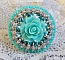 Bague Blue Flowers brod&eacute;e avec un cabochon en forme de rose en r&eacute;sine, cha&icirc;ne strass Cristal, toupies Jet de haute qualit&eacute; AB2X et farfalles ovales. Les couleurs sont : l&rsquo;Argent&eacute; et le Vert Menthe