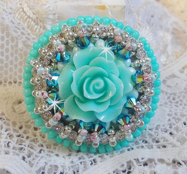 Bague Blue Flowers brod&eacute;e avec un cabochon en forme de rose en r&eacute;sine, cha&icirc;ne strass Cristal, toupies Jet de haute qualit&eacute; AB2X et farfalles ovales. Les couleurs sont : l&rsquo;Argent&eacute; et le Vert Menthe