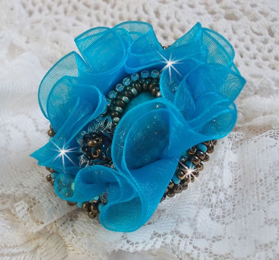 Bague artisanale brodée avec fleur en ruban bleu turquoise.