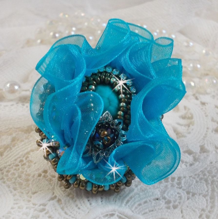 Bague artisanale brodée avec cabochon turquoise et fleur bleue.