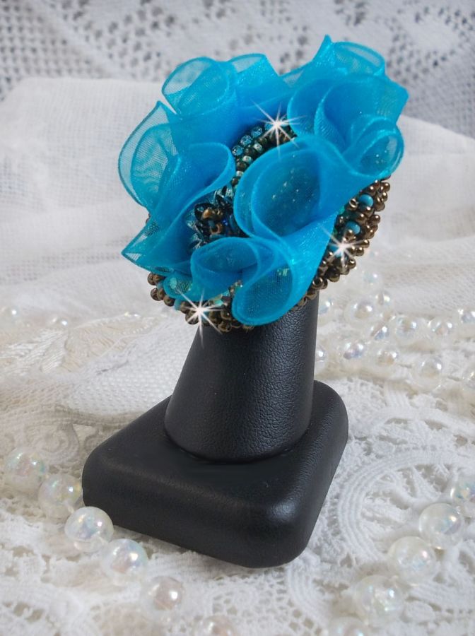 Bague artisanale brodée bleu turquoise avec fleurs en cristal.