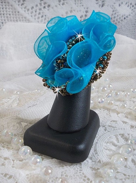 Bague artisanale brodée bleu turquoise avec fleurs en cristal.