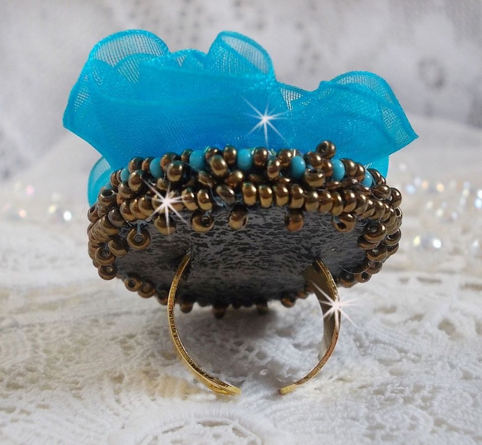 Bague artisanale réglable avec fleur bleue et perles dorées.