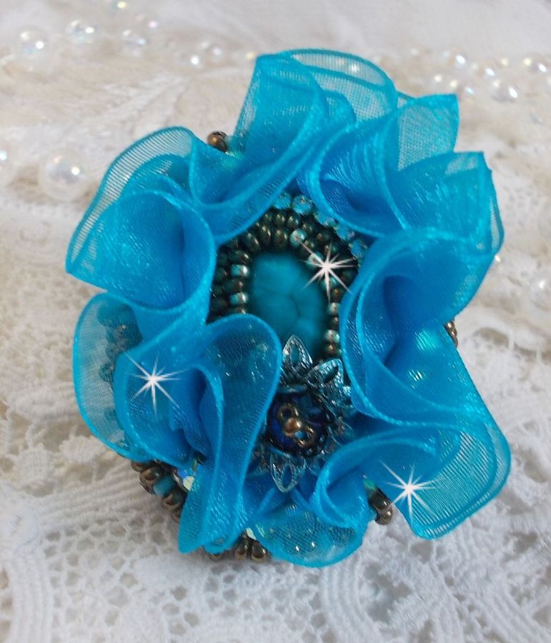 Bague artisanale bleue turquoise brodée avec cristaux et rubans.